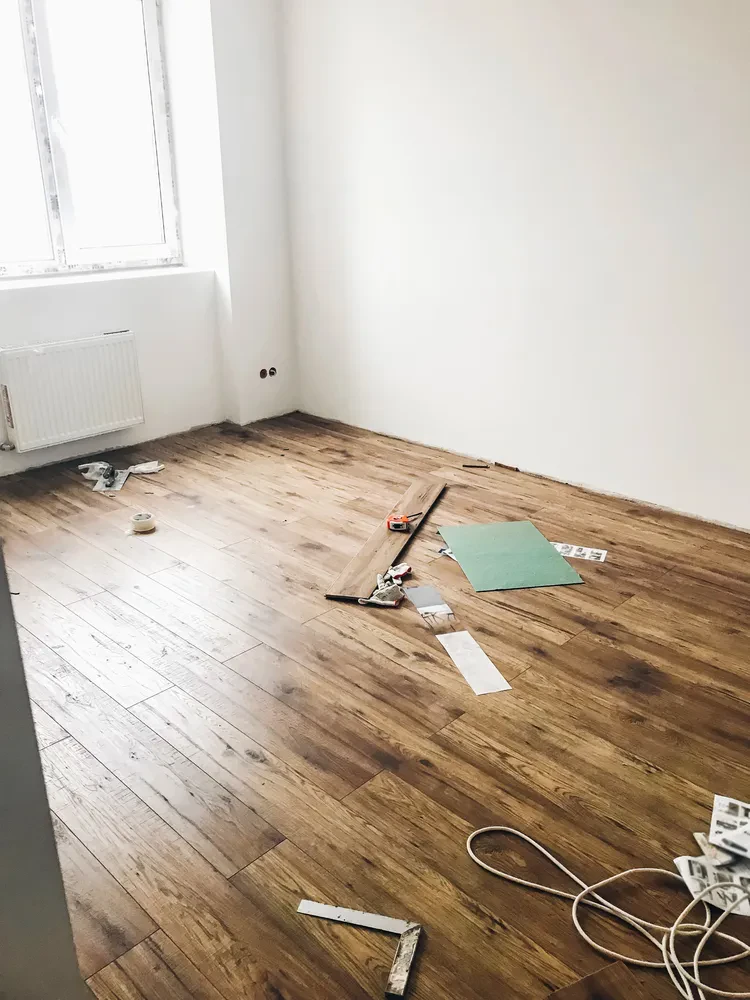 Polaganje lesenih talnih oblog v modernem prostoru Delavci strokovno polagajo trde lesene planke parketa v svetlem prostoru z modernimi belimi stenami, kar zagotavlja kvalitetno polaganje parketa Laško, okolica.