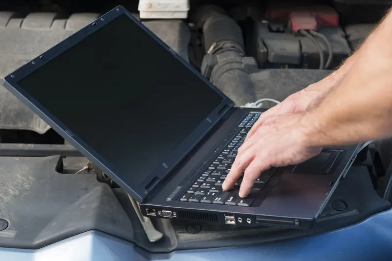 Diagnostika motorja z računalnikom Mehanik uporablja prenosni računalnik za diagnostiko motorja avtomobila, ki ima odprt pokrov.